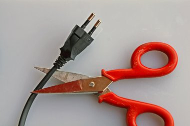 Scissors that cuts the electric cord of a black plug clipart