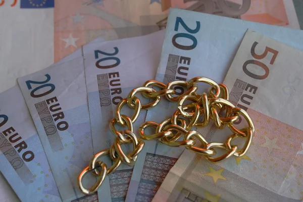 Colar de ouro com dinheiro em euros em segundo plano — Fotografia de Stock