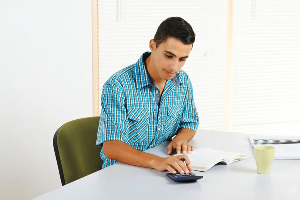 Young man using a calculator — Stock Photo, Image