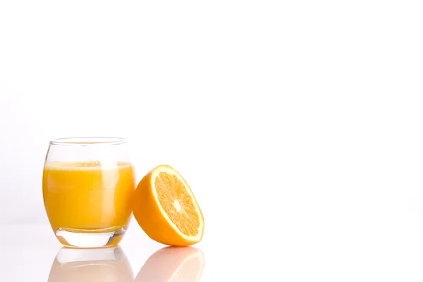 stock image Composition of a glass with a refreshing orange juice and the half of a ora