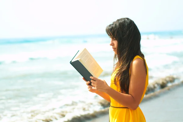 stock image Young lady reading a book on the beach