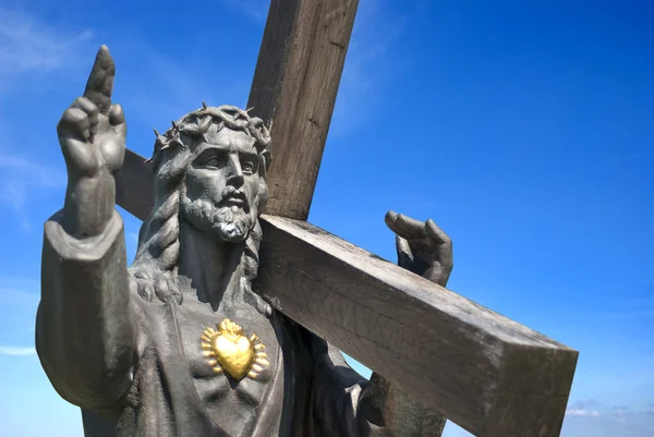 Jezus trzyma krzyż na niebieskim tle — Zdjęcie stockowe