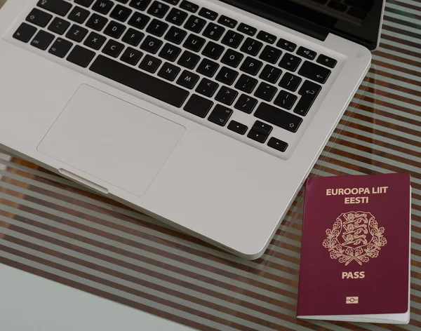 Laptop, passaporte colocado em uma mesa de vidro . Fotos De Bancos De Imagens