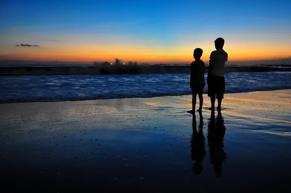 Два мальчика силуэты на закате океана — стоковое фото