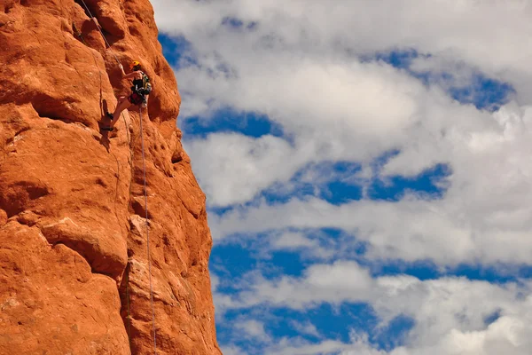 Альпинист на красной скале — стоковое фото