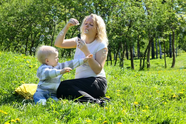 Мать и ребенок играют на зеленом поле — стоковое фото
