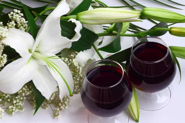 Bukiet lilii i dwie szklanki czerwonego wina — Zdjęcie stockowe