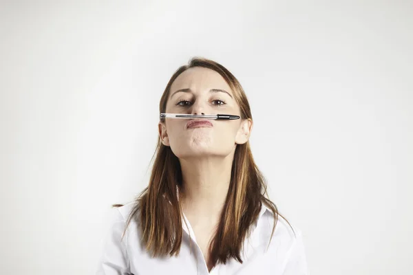 Молода бізнес-леді тримає ручку носом — стокове фото