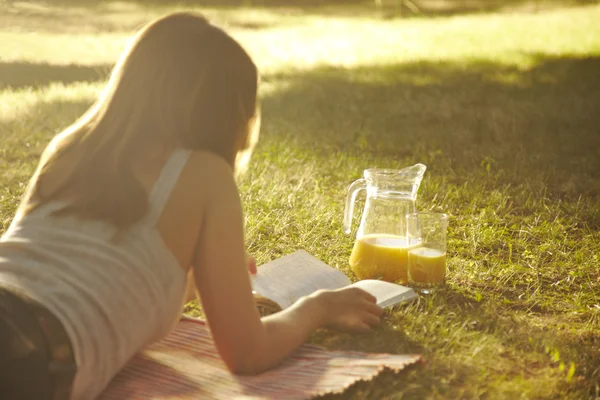 Nette junge Frau liest draußen — Stockfoto