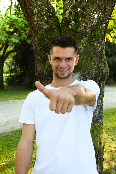 나무 앞에서 엄지손가락을 내밀고 있는 사람 — 스톡 사진
