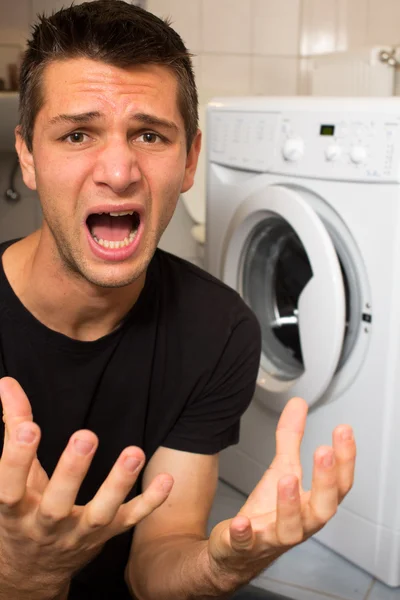 Молодой человек недоволен стиральной машиной — стоковое фото