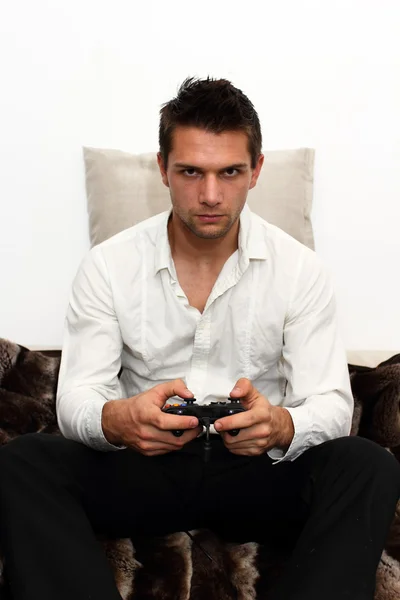 Gamer sitting on couch with controller and playing — Stock Photo, Image