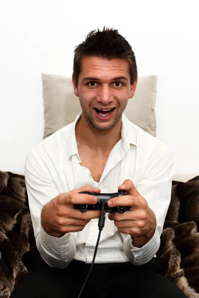 Glimlachend gamer vergadering op Bank met controller en spelen — Stockfoto
