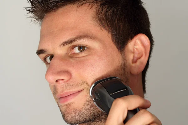 Hombre afeitado cara con maquinilla de afeitar eléctrica — Foto de Stock