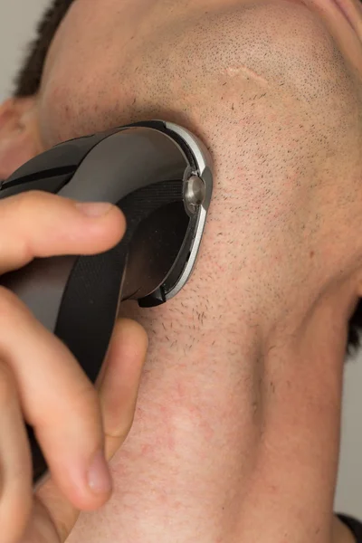 stock image Man shaving face with electric razor