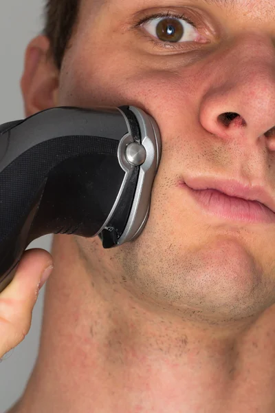 Мужчина бреет лицо электрической бритвой — стоковое фото