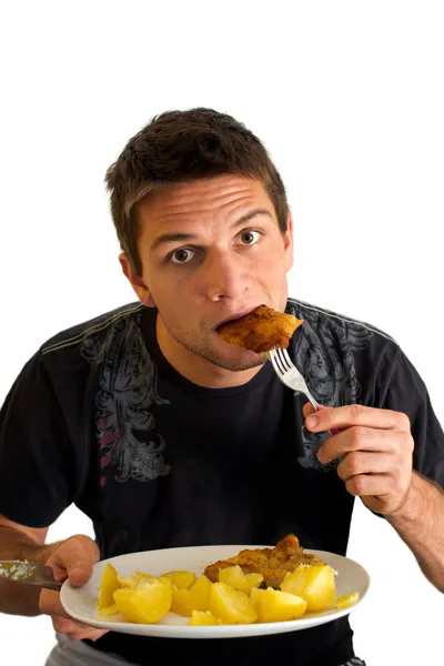 Jonge man eten een schnitzel en aardappelen — Stockfoto