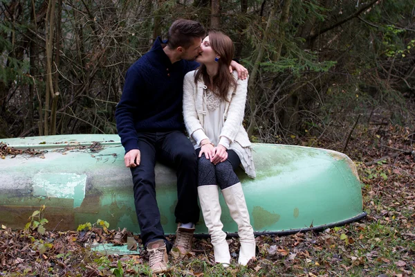 Um jovem casal bonito sentado em um velho barco — Fotografia de Stock