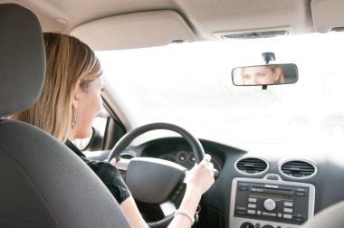 Portrait of young smiling woman driving car clipart