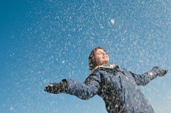 Наслаждаясь зимой - женщина бросает снег — стоковое фото
