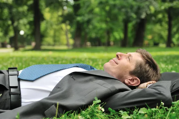 Senior business man lying in grass — Stock Photo, Image