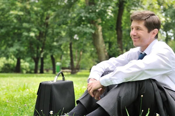 stock image Senior business man siting in grass