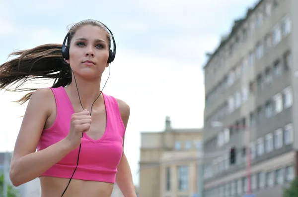 Young person listening misic running in city street — Stock Photo, Image