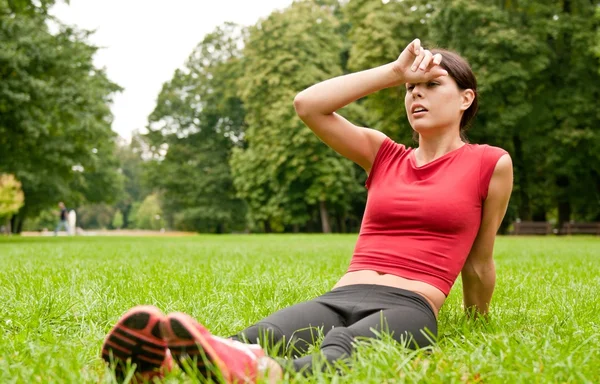 Отдых в траве - уставшая женщина после занятий спортом — стоковое фото
