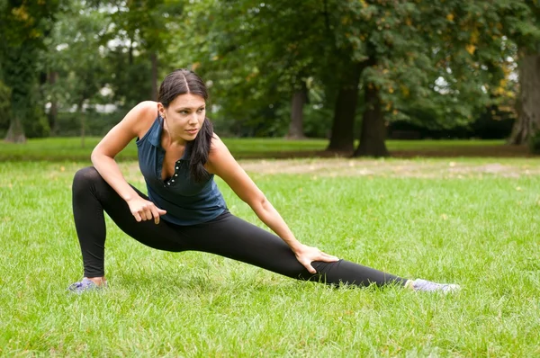 Mulher realiza alongamento antes do esporte no parque — Fotografia de Stock