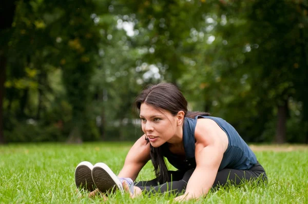 Woman performs stretching before sport in park — Stock Photo, Image