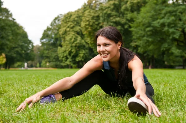 Ontspannen - Sportvrouw zitten in gras — Stockfoto