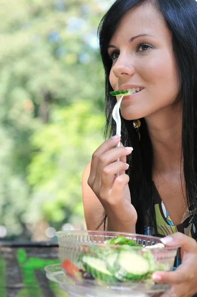 Mladá žena jíst salát venku — Stock fotografie