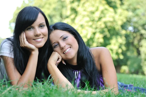 Two happy sisters lying outdoors in grass — Stock Photo, Image