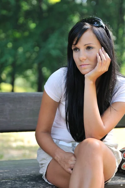 Jovem mulher pensativa sentado no banco — Fotografia de Stock