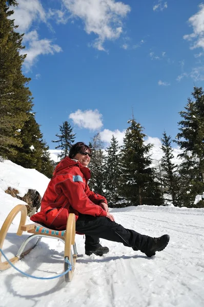 Mature woman on sledge sunning in winter — Stock Photo, Image