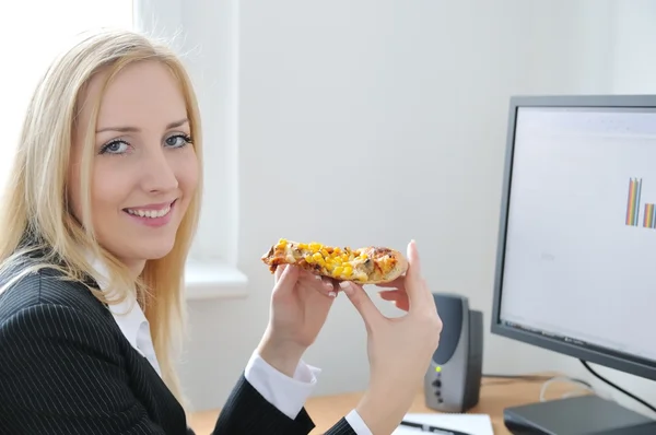 Молодая деловая женщина ест пиццу на работе — стоковое фото