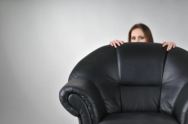 Young woman hiding behind big armchair — Stock Photo, Image