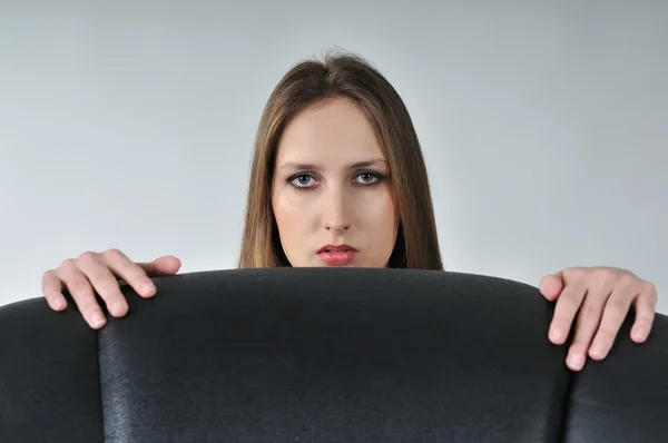 Jovem mulher se escondendo atrás de poltrona grande — Fotografia de Stock