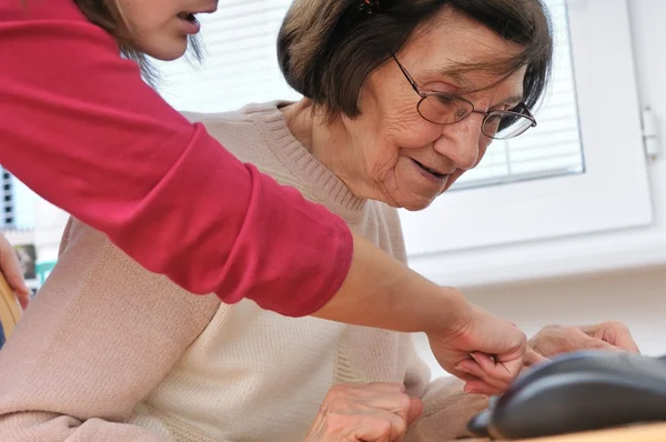 Молодая женщина учит свою бабушку работать с компьютером — стоковое фото