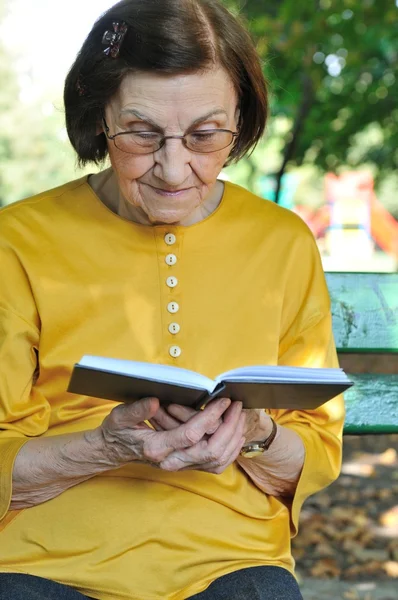 シニアの女性の読書本 autdoors — ストック写真