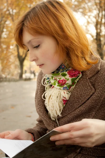 Tyttö lukeminen kirja syksyllä puistossa — kuvapankkivalokuva