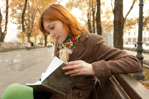 Tyttö lukeminen kirja syksyllä puistossa — kuvapankkivalokuva