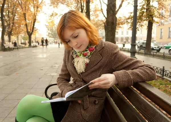 Punapää tyttö käsittelyssä syksyllä puistossa — kuvapankkivalokuva