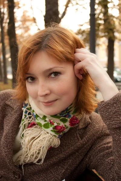Ragazza sorridente con sciarpa fiorita nel parco autunnale — Foto Stock