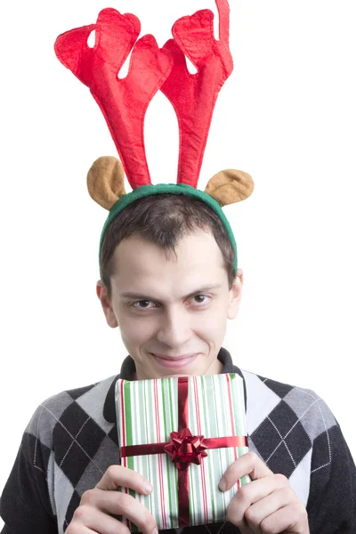 Happy man in Christmas party elk horns holding red gift box — Stock Photo, Image