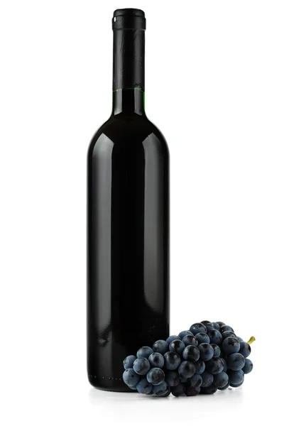 Una botella de vino tinto y uvas . — Foto de Stock
