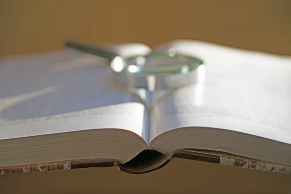 Open book with magnifying glass — Stock Photo, Image