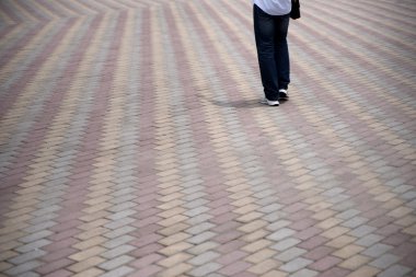 Person walking on tiled pedestrian road clipart