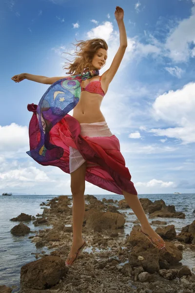 Chica saltando en una playa. el telón de fondo del océano — Foto de Stock