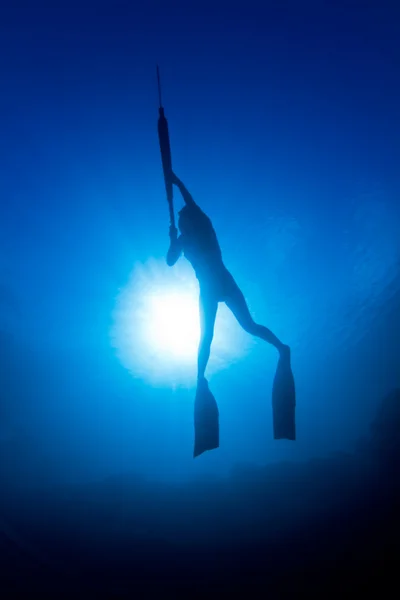 A girl spearfishing infront of the sun — Stock Photo, Image